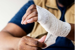 A close-up of a person with a bandaged wrist, securing it with self-adhesive wrap for protection.