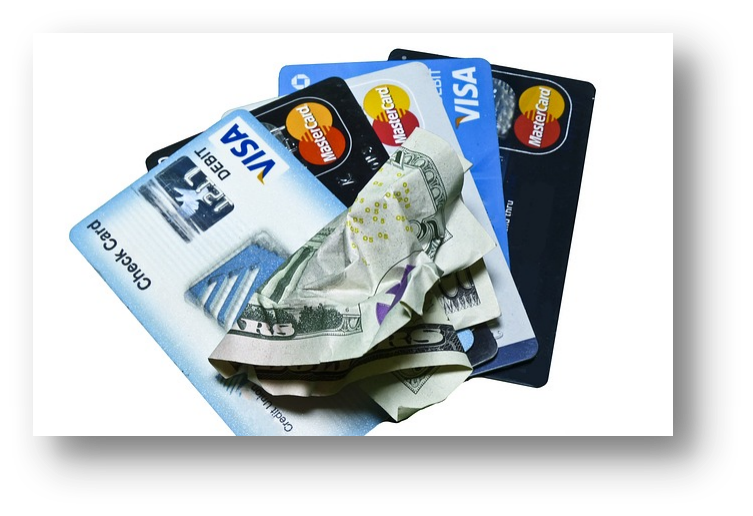 Stack of credit and debit cards with crumpled cash, representing payment options and financial transactions